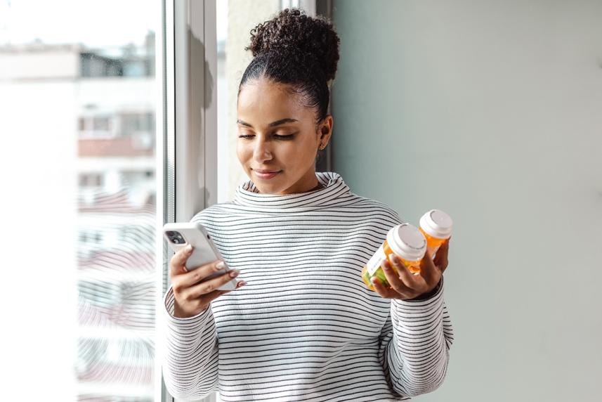 Adult female looking at phone while holding bottles