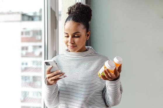Adult female looking at phone while holding bottles